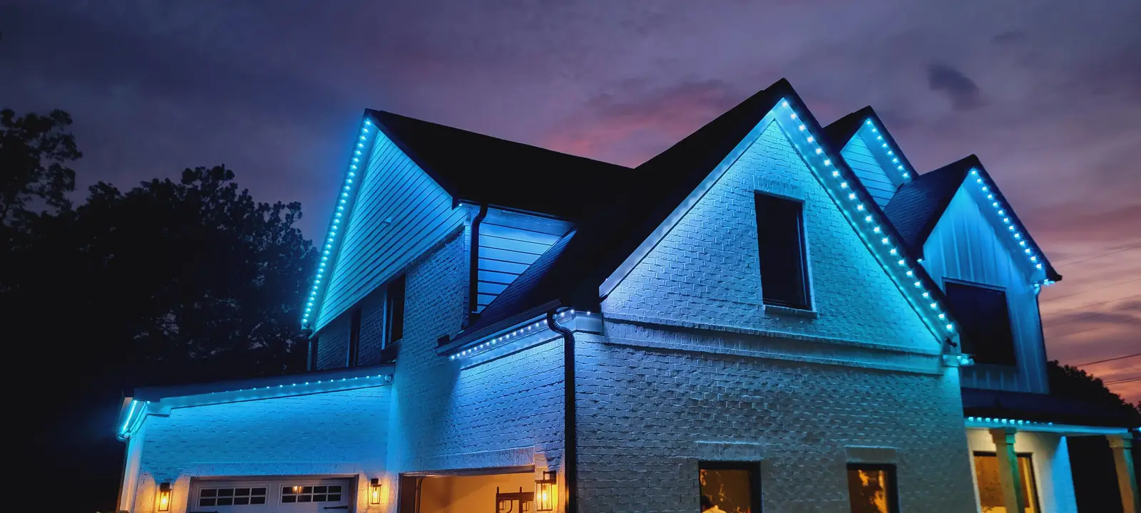 Blue house at night with permanent roofline lighting